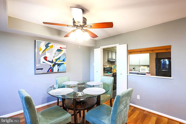 dining area with ceiling fan and dark hardwood / wood-style flooring