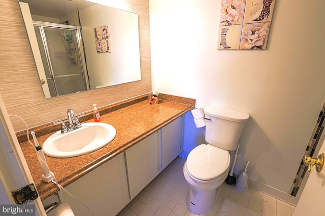 bathroom featuring toilet, vanity, tile patterned floors, and an enclosed shower