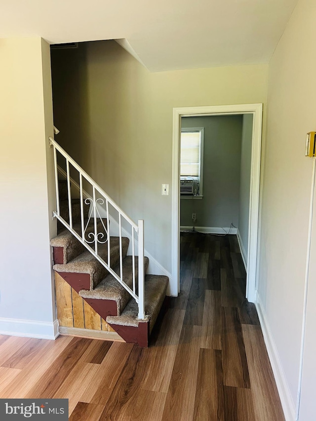 stairs with hardwood / wood-style flooring and cooling unit