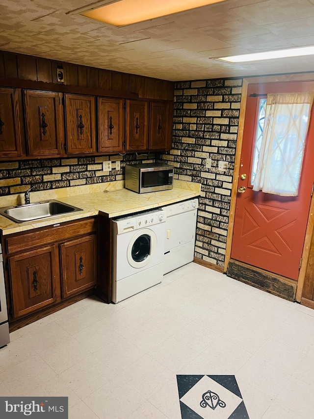 kitchen featuring white dishwasher, dark brown cabinetry, sink, and brick wall