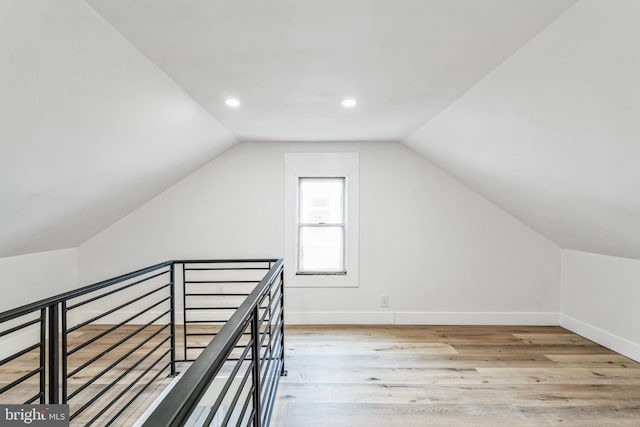 additional living space featuring light wood-type flooring and vaulted ceiling