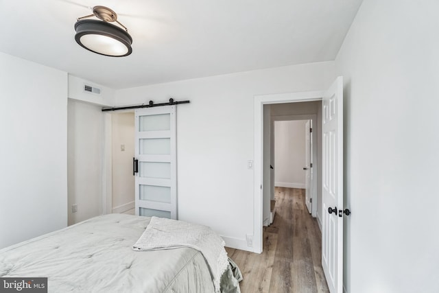 bedroom with a barn door and light hardwood / wood-style floors