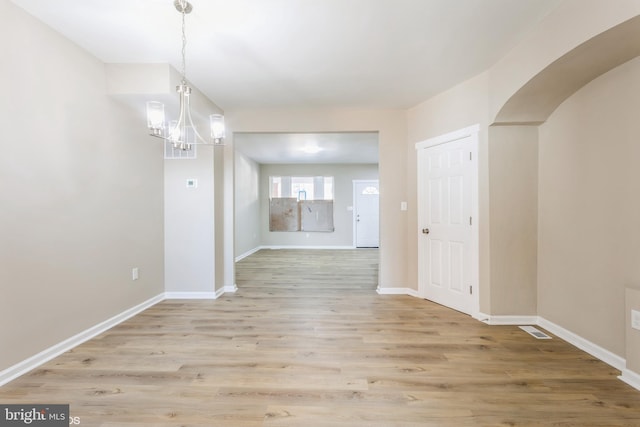 unfurnished dining area with light hardwood / wood-style floors and a notable chandelier