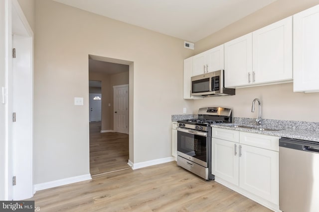 kitchen featuring white cabinets, light stone countertops, sink, and appliances with stainless steel finishes