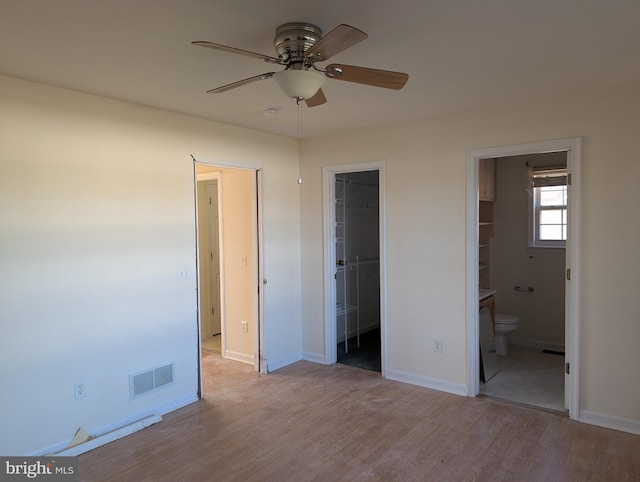 unfurnished bedroom with connected bathroom, a spacious closet, ceiling fan, light hardwood / wood-style flooring, and a closet