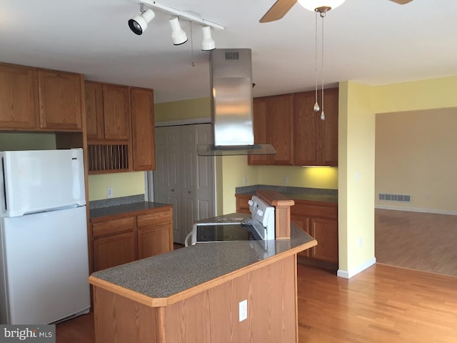 kitchen with white appliances, ceiling fan, light wood-type flooring, a kitchen island, and extractor fan