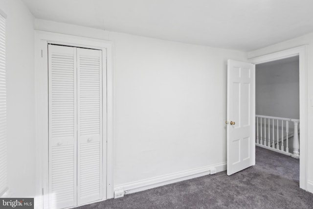 unfurnished bedroom featuring dark colored carpet and a closet