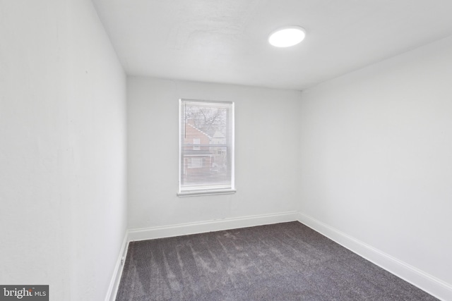 spare room with dark colored carpet