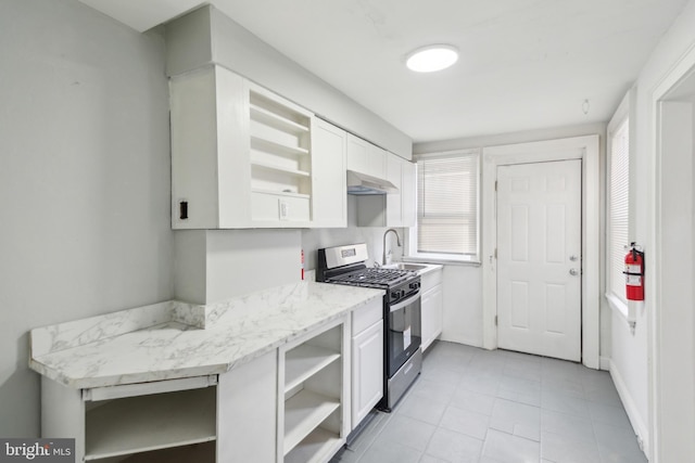 kitchen featuring stainless steel range with gas cooktop, sink, white cabinets, and range hood