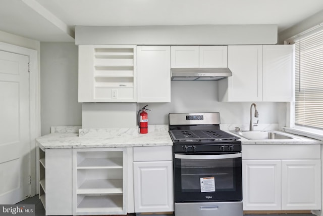 kitchen featuring light stone countertops, gas stove, sink, white cabinetry, and range hood