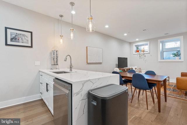 kitchen with light stone countertops, sink, dishwasher, white cabinetry, and hanging light fixtures