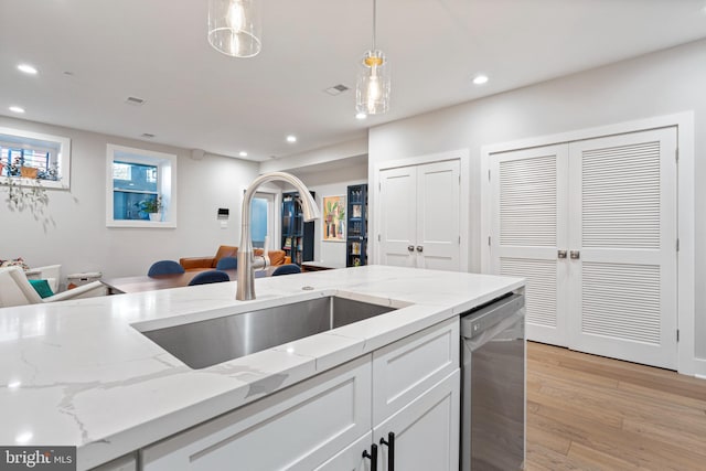 kitchen featuring sink, hanging light fixtures, stainless steel dishwasher, light stone counters, and white cabinetry