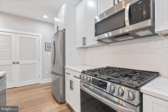 kitchen featuring backsplash, light stone counters, white cabinets, and appliances with stainless steel finishes