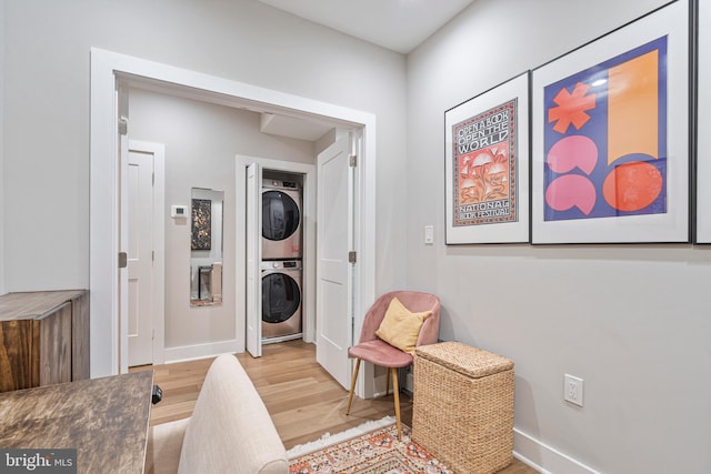 laundry area featuring stacked washer / dryer and light hardwood / wood-style floors