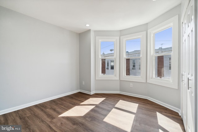 spare room with dark hardwood / wood-style flooring and plenty of natural light