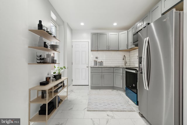 kitchen featuring decorative backsplash, appliances with stainless steel finishes, light stone countertops, sink, and gray cabinets