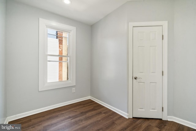 unfurnished room with vaulted ceiling and dark wood-type flooring