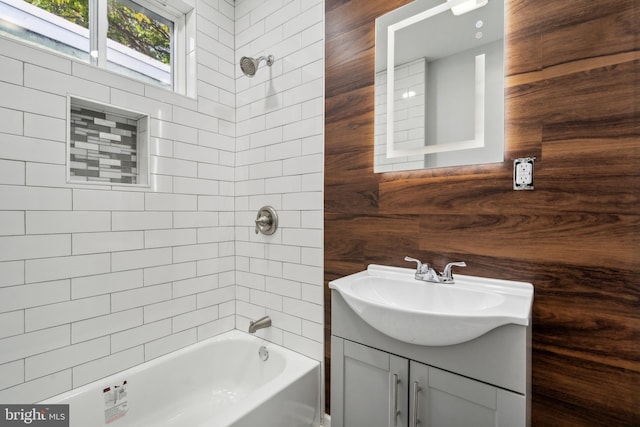 bathroom with vanity, tiled shower / bath combo, and wood walls