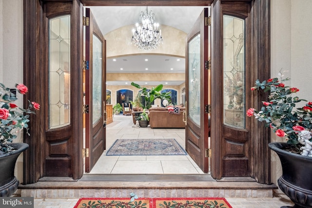 foyer entrance featuring a notable chandelier, lofted ceiling, and french doors