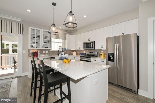 kitchen with a kitchen island, light stone counters, plenty of natural light, white cabinets, and appliances with stainless steel finishes