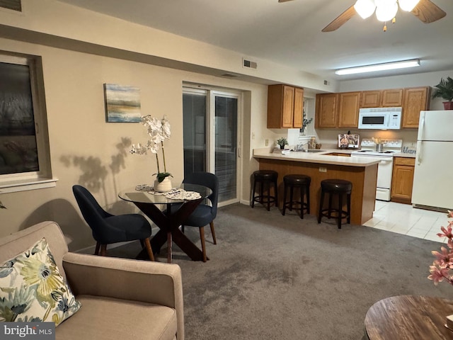 interior space featuring light carpet, white appliances, brown cabinetry, a breakfast bar, and light countertops