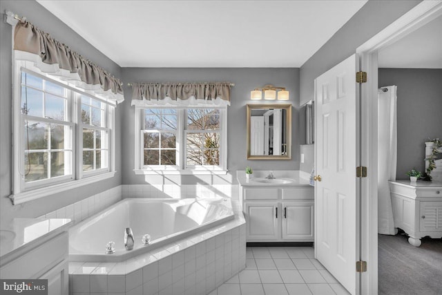 bathroom featuring vanity, a relaxing tiled tub, tile patterned floors, and a healthy amount of sunlight