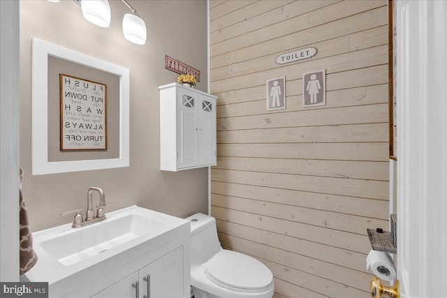 bathroom featuring vanity, toilet, and wooden walls