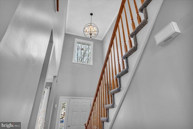 foyer entrance with a high ceiling, crown molding, and a notable chandelier