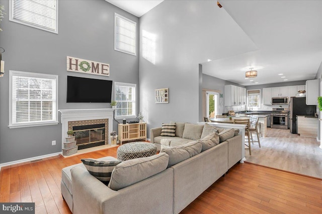 living room featuring a high end fireplace, a high ceiling, and light hardwood / wood-style flooring