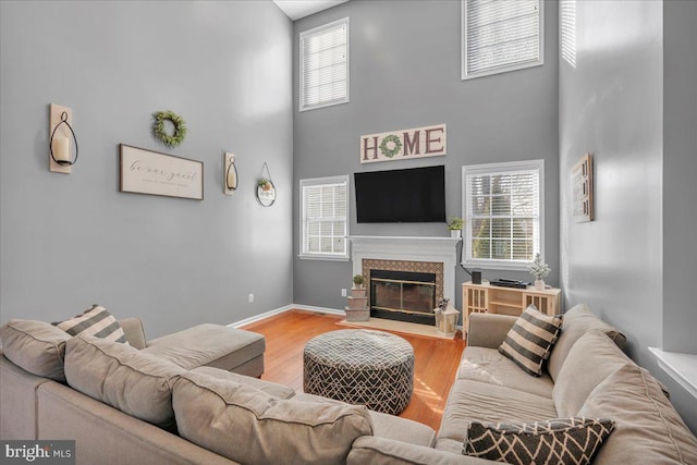 living room with plenty of natural light, a high ceiling, and light hardwood / wood-style flooring