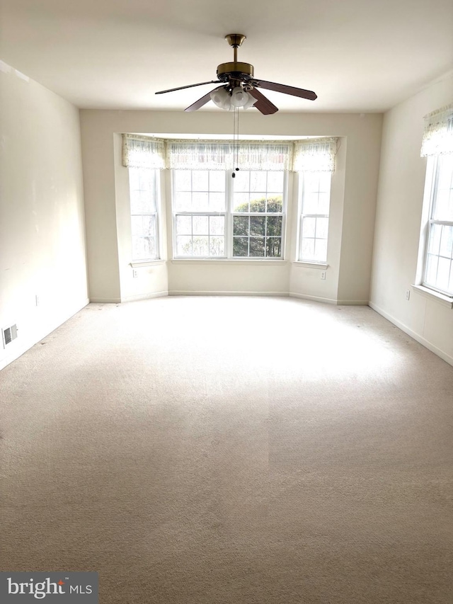 carpeted empty room with ceiling fan and a healthy amount of sunlight