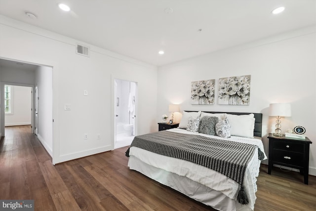 bedroom with ornamental molding, dark wood-type flooring, and connected bathroom