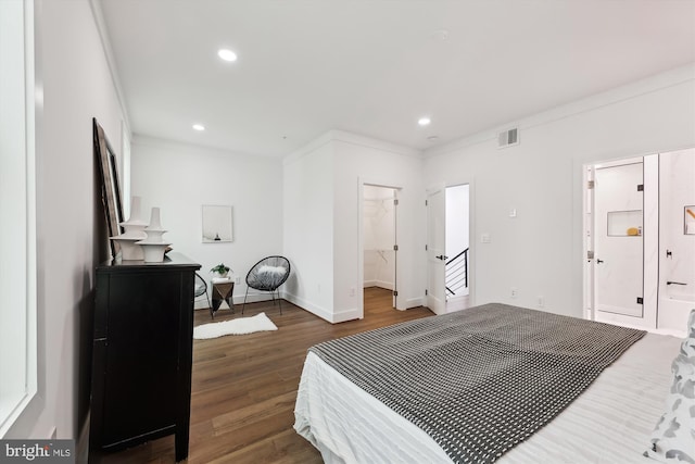 bedroom with a spacious closet, a closet, crown molding, and dark hardwood / wood-style floors