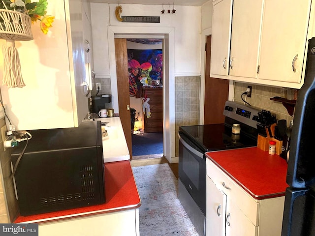 kitchen with white cabinetry, fridge, electric stove, and decorative backsplash