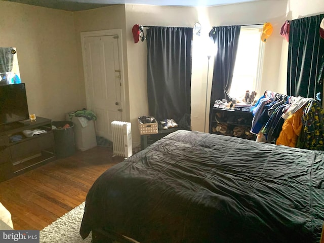 bedroom with radiator heating unit and hardwood / wood-style floors