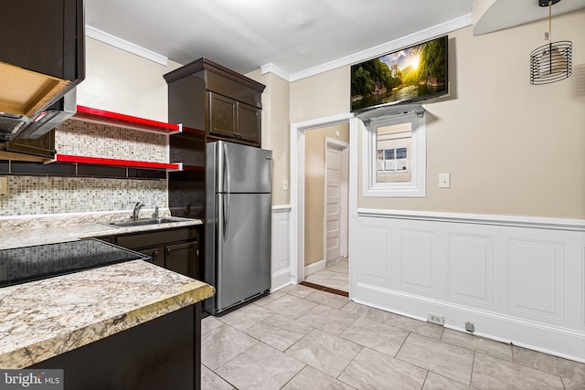 kitchen featuring stainless steel refrigerator, sink, dark brown cabinets, and ornamental molding