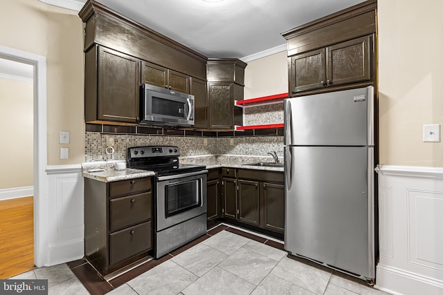 kitchen with light stone countertops, sink, stainless steel appliances, dark brown cabinets, and ornamental molding