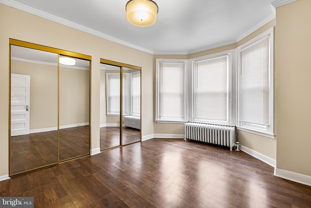 unfurnished bedroom with crown molding, radiator heating unit, and two closets