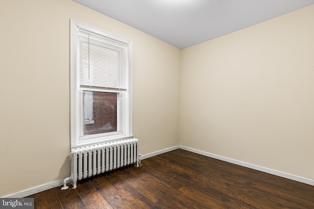 empty room with dark wood-type flooring and radiator