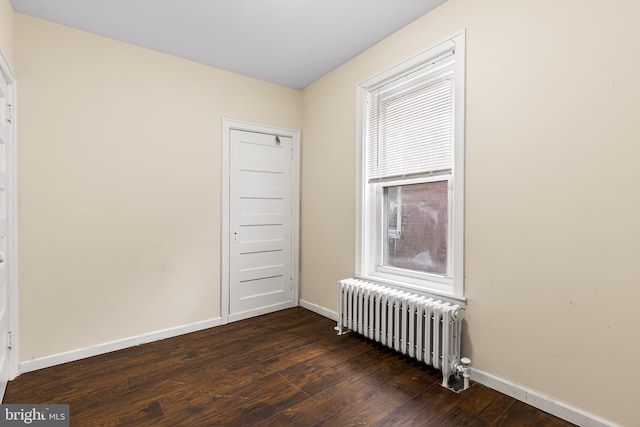 unfurnished room with dark hardwood / wood-style floors and radiator