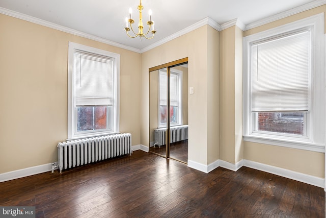 spare room featuring a notable chandelier, radiator heating unit, crown molding, and dark wood-type flooring