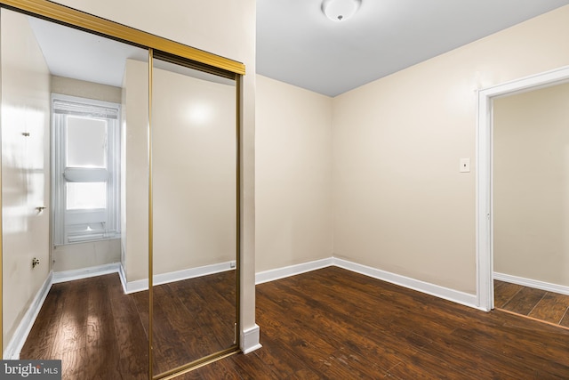 unfurnished bedroom with dark hardwood / wood-style flooring and a closet