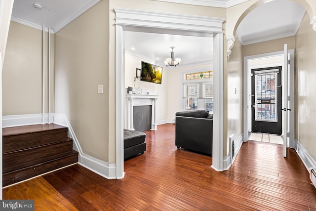 entryway featuring hardwood / wood-style floors, crown molding, and a notable chandelier