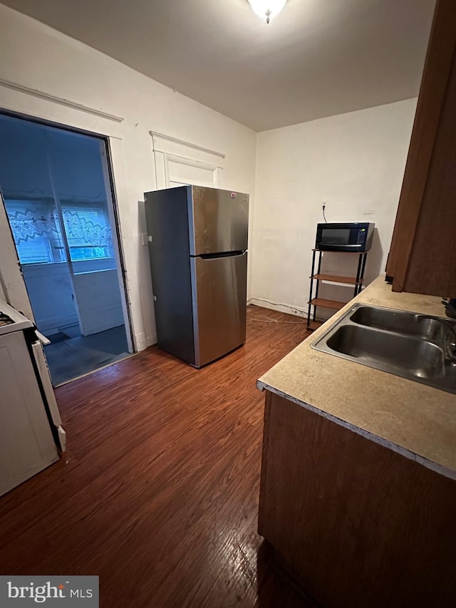 kitchen featuring dark hardwood / wood-style flooring, stainless steel fridge, sink, and range