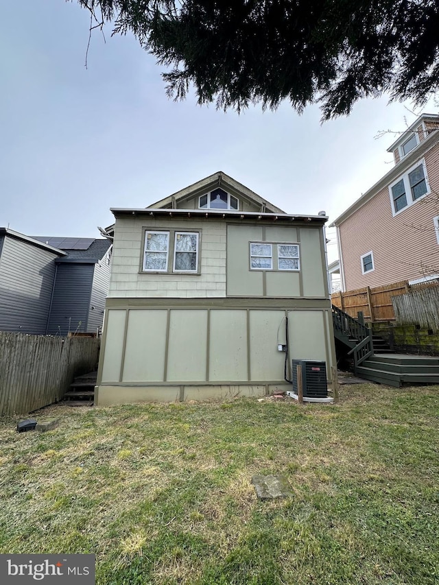 back of house with a lawn and central air condition unit