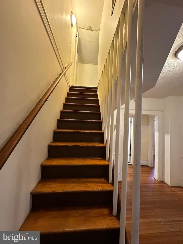 stairway featuring hardwood / wood-style floors and a textured ceiling