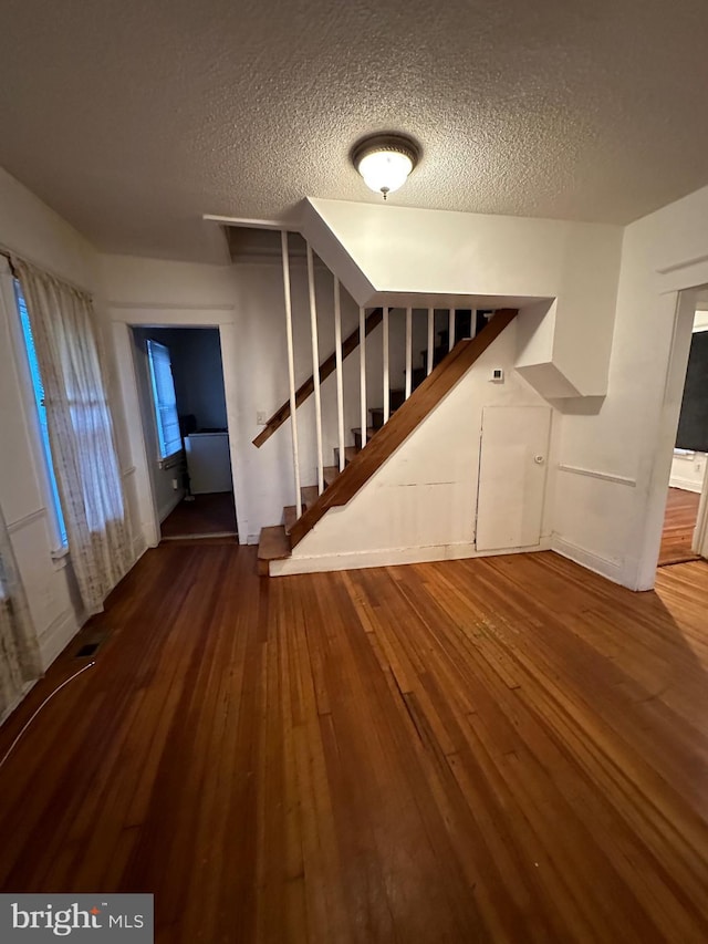 staircase with hardwood / wood-style flooring and a textured ceiling