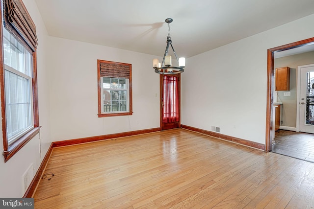 unfurnished dining area with light hardwood / wood-style flooring and an inviting chandelier