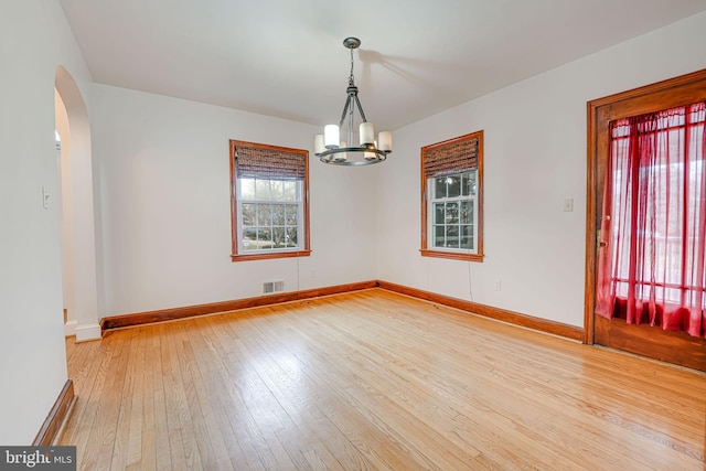 empty room featuring hardwood / wood-style flooring and an inviting chandelier