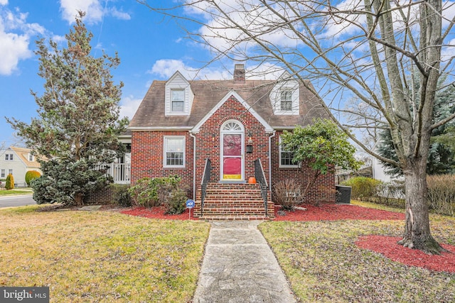 cape cod house featuring central AC unit and a front lawn